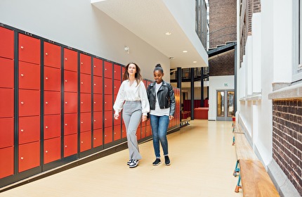 Jeugdverpleegkundige en leerling maken een praatje in de gang van een middelbare school